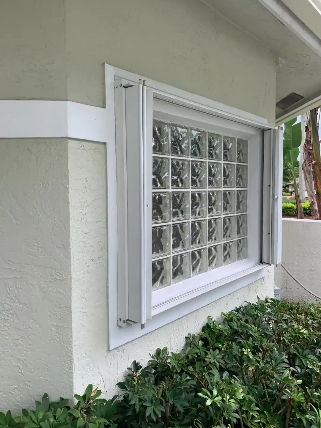 Cream accordion hurricane shutters closed across a wide sliding glass door