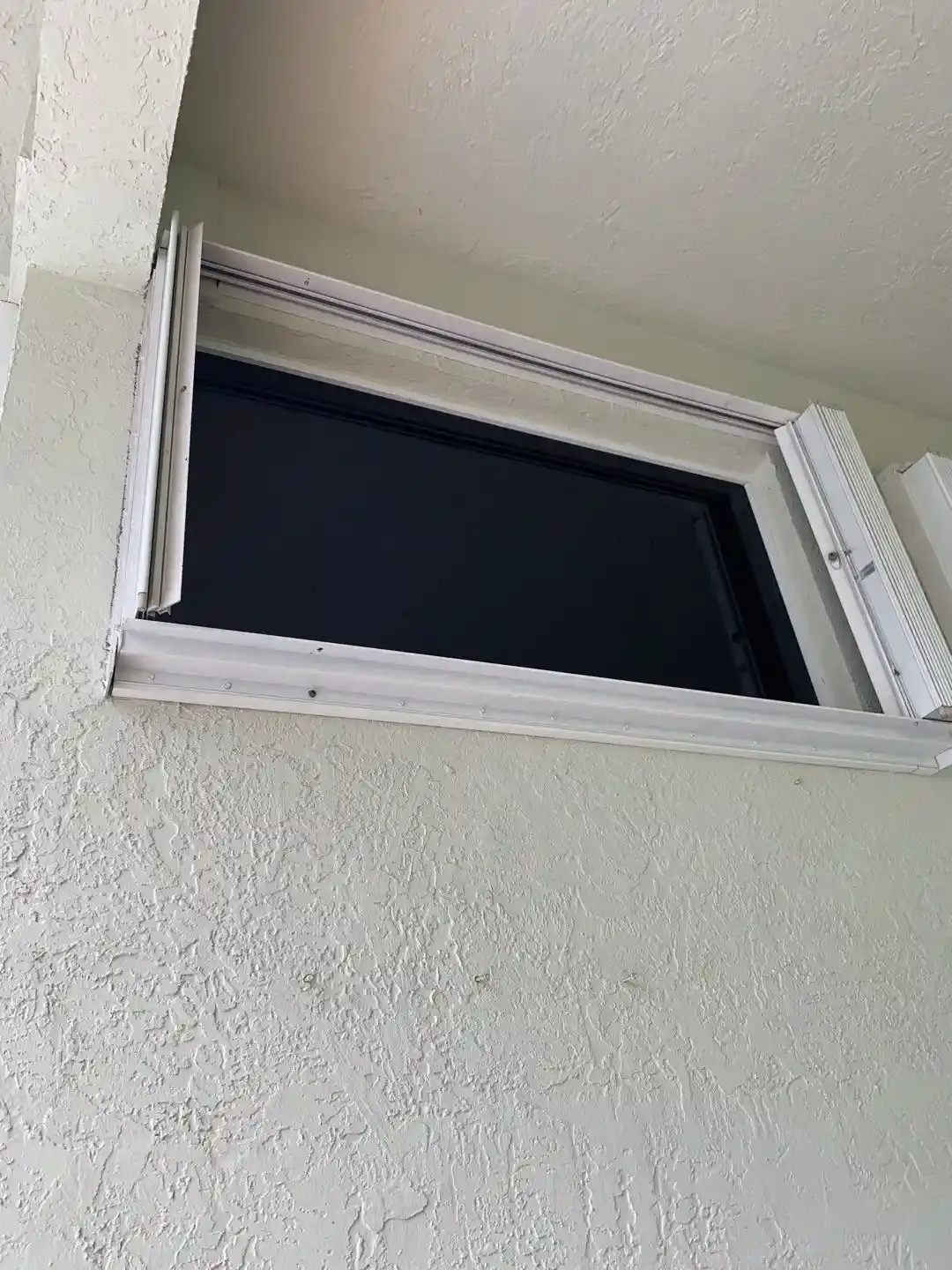 Accordion shutter partly drawn across a window opening showing the interlocking blades
