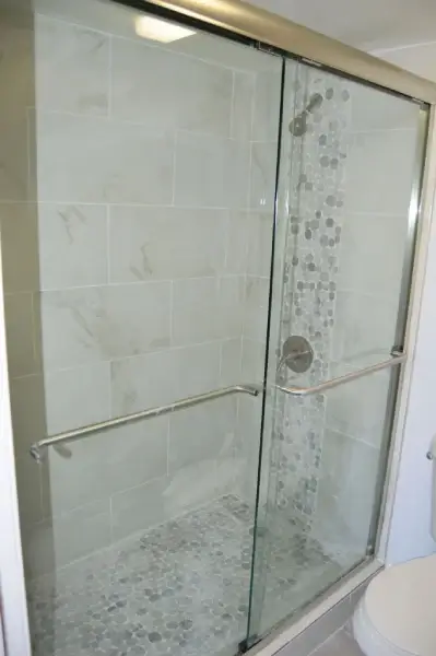 Remodeled bathroom with a frameless glass shower enclosure and marble-look tile