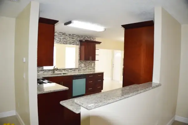 Kitchen opened up to the living area with a granite peninsula and dark wood cabinets