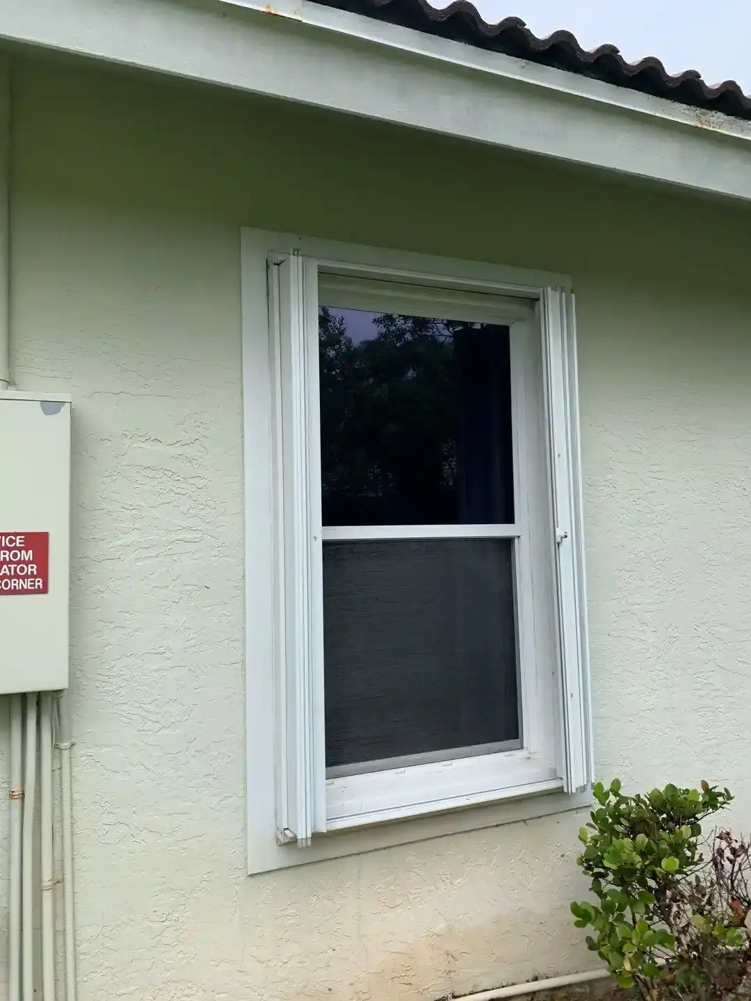Cream accordion shutters installed over windows on a South Florida home
