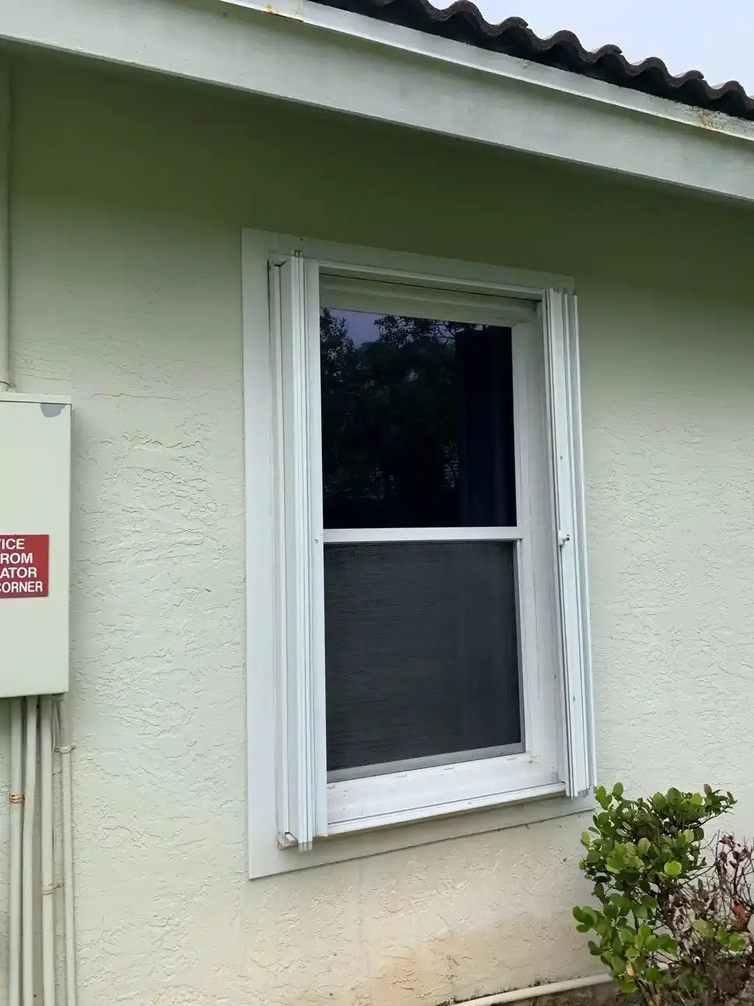 Cream accordion shutters installed over a sliding glass door