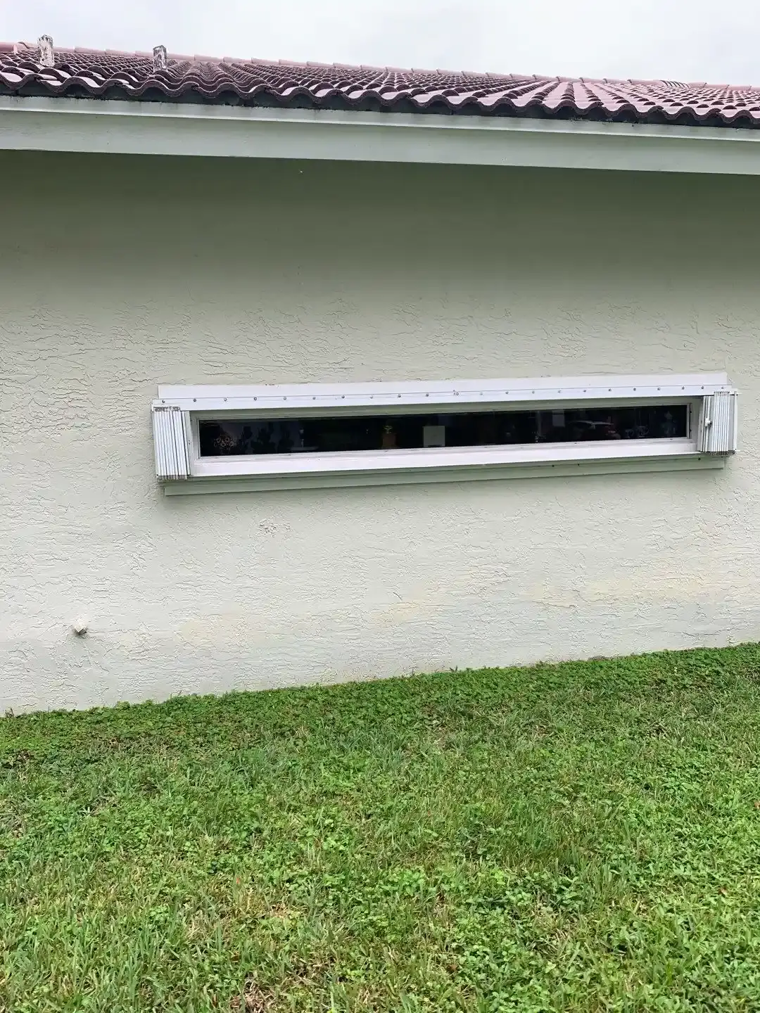 Accordion hurricane shutters installed along the rear elevation of a house