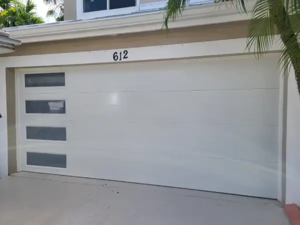 White sectional garage door with a row of glass panels installed on a South Florida house