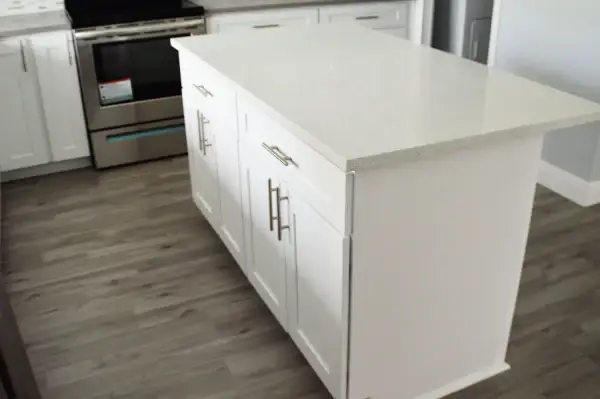 Remodeled kitchen with white cabinets and a large quartz island