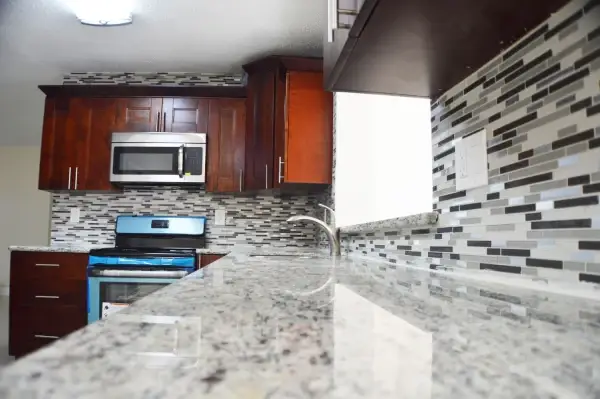 Dark wood cabinet kitchen remodel with granite counters and glass tile backsplash
