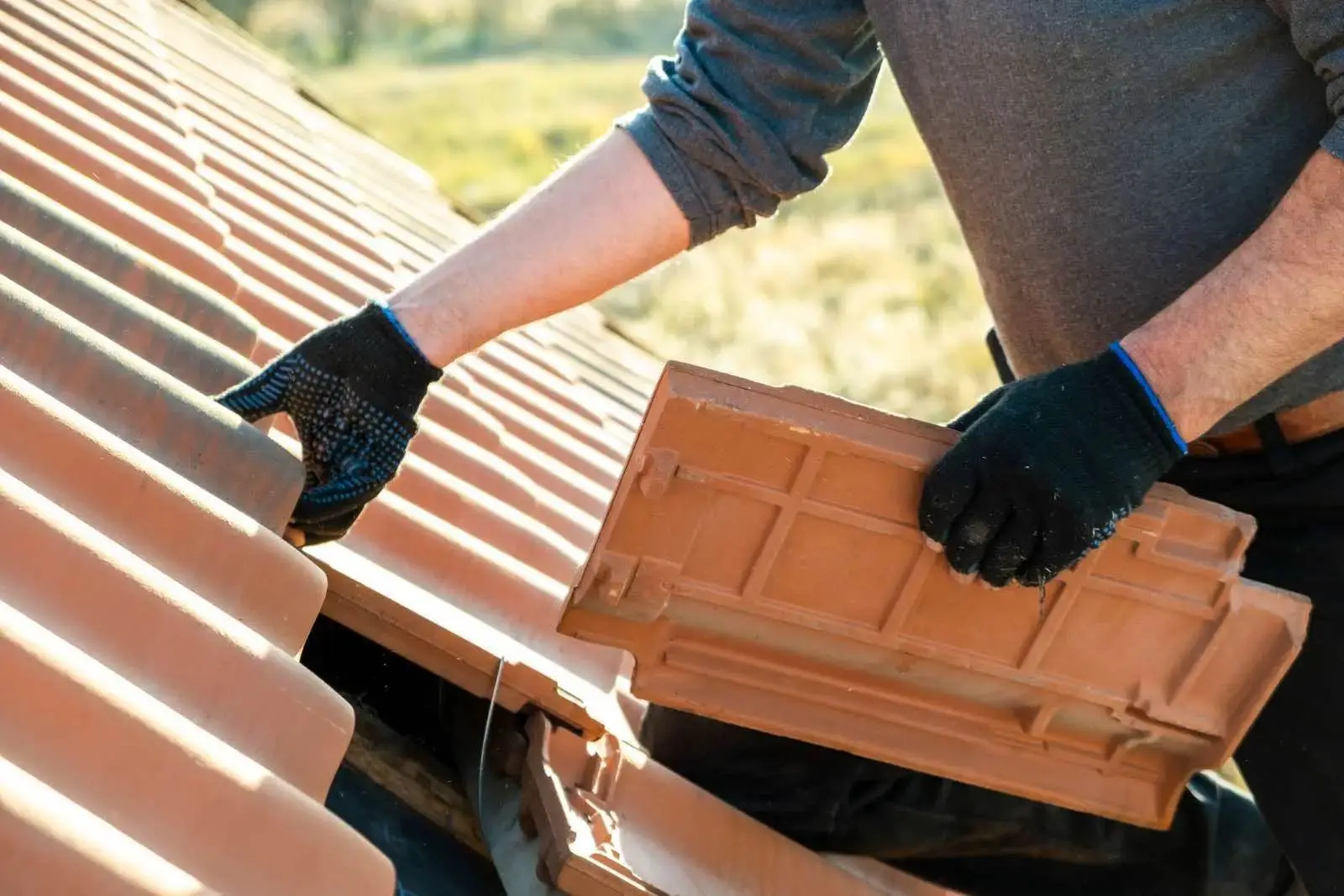 Gloved hands setting a terracotta profile tile into place on a South Florida tile roof